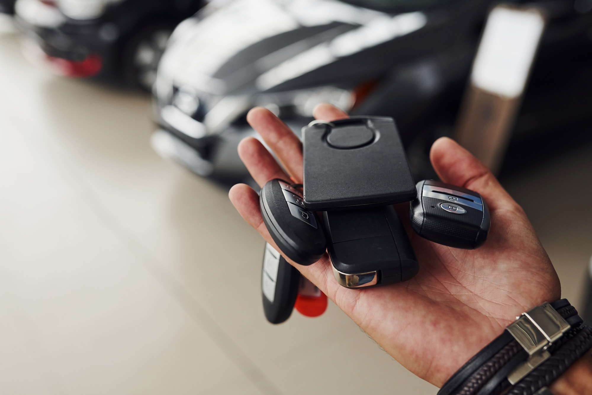 Keys from the cars lying on man's hand. Indoors in auto salon